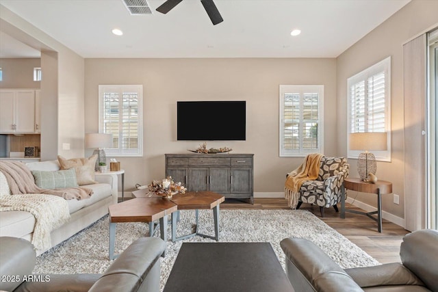 living room with visible vents, baseboards, light wood-type flooring, and ceiling fan