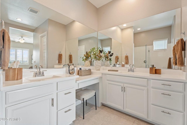 bathroom featuring double vanity, a shower with shower door, visible vents, and a sink