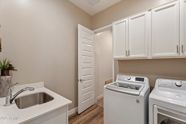 laundry room with light wood finished floors, visible vents, separate washer and dryer, cabinet space, and a sink