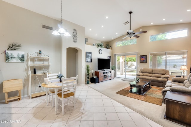 living area featuring light tile patterned floors, visible vents, arched walkways, and light colored carpet