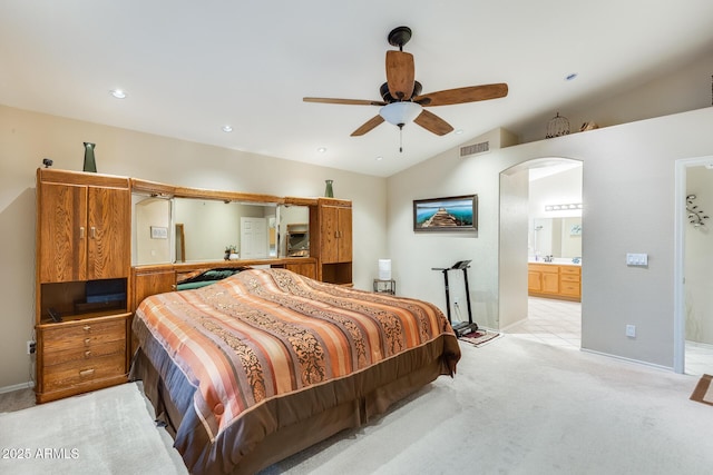 bedroom featuring visible vents, light carpet, connected bathroom, arched walkways, and vaulted ceiling