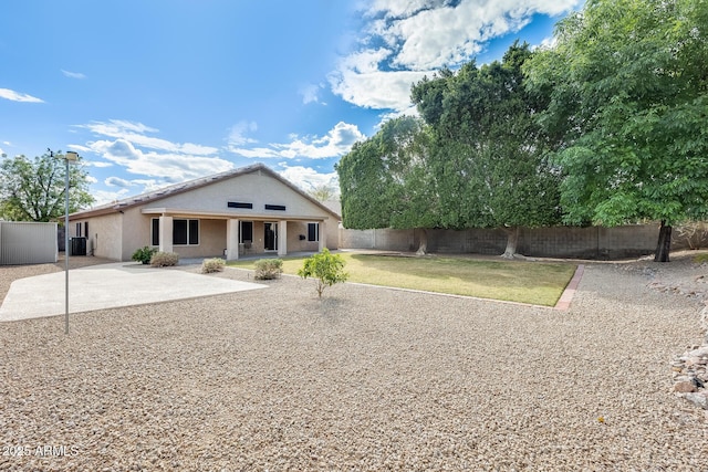 rear view of property featuring stucco siding, a lawn, central AC, a fenced backyard, and a patio area