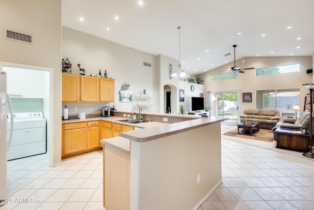 kitchen featuring visible vents, light brown cabinets, light tile patterned flooring, washer / clothes dryer, and a sink