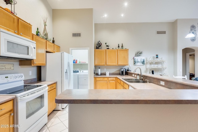 kitchen featuring white appliances, visible vents, arched walkways, a sink, and washer and clothes dryer