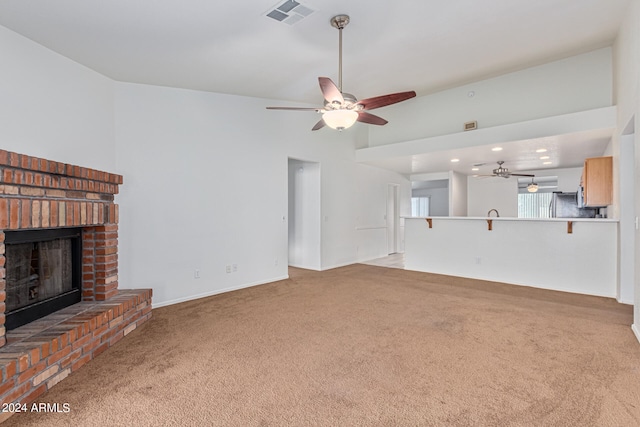 unfurnished living room featuring ceiling fan, light colored carpet, and a brick fireplace