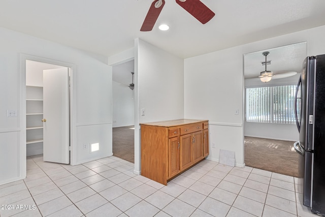 kitchen featuring ceiling fan, stainless steel refrigerator, pendant lighting, and light colored carpet