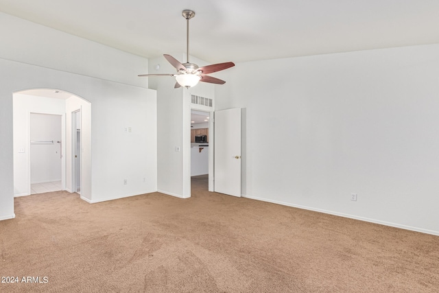 unfurnished bedroom featuring ceiling fan, vaulted ceiling, a spacious closet, and light carpet