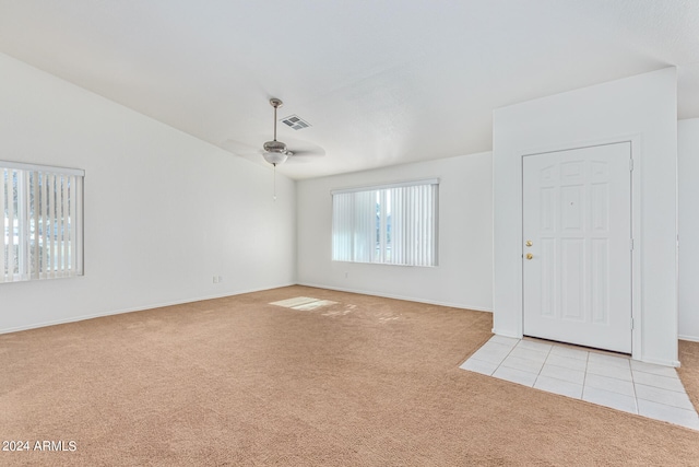 interior space with ceiling fan, vaulted ceiling, and light carpet