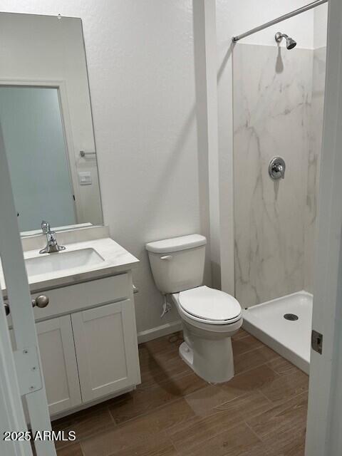 bathroom with vanity, a tile shower, and toilet