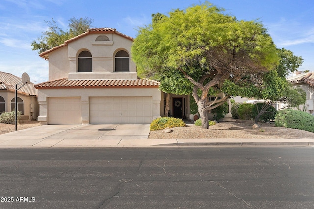 mediterranean / spanish house with a garage, stucco siding, a tiled roof, and concrete driveway