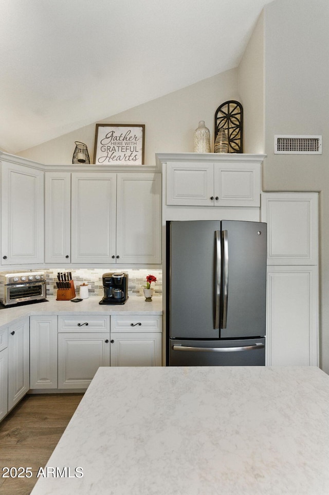 kitchen featuring visible vents, freestanding refrigerator, lofted ceiling, and wood finished floors