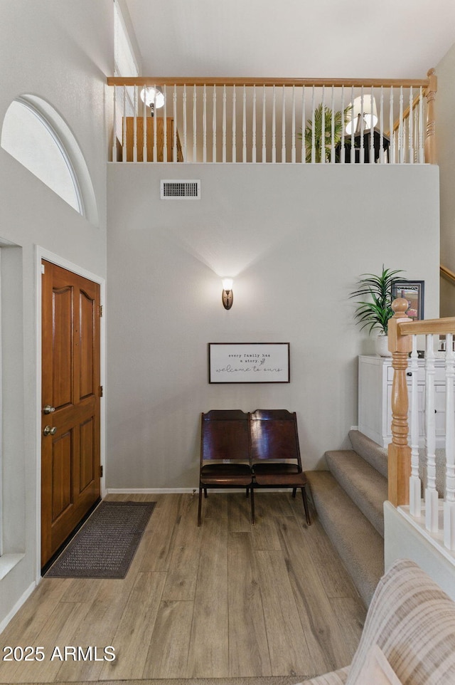 foyer featuring visible vents, wood finished floors, and stairway