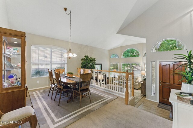 dining area with an inviting chandelier, baseboards, and high vaulted ceiling