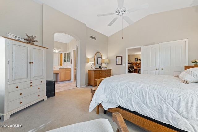 bedroom featuring visible vents, light carpet, ensuite bathroom, high vaulted ceiling, and arched walkways