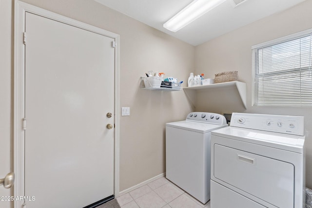 clothes washing area featuring laundry area, washer and clothes dryer, baseboards, and light tile patterned floors