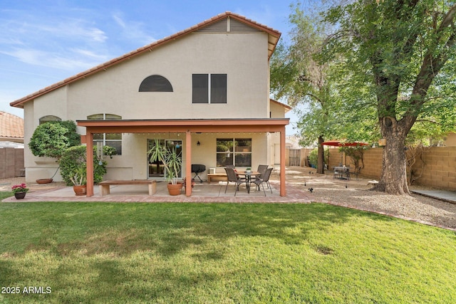 rear view of property with a fenced backyard, stucco siding, a lawn, and a patio area