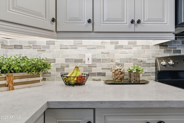 interior details with range with electric stovetop, backsplash, and white cabinets