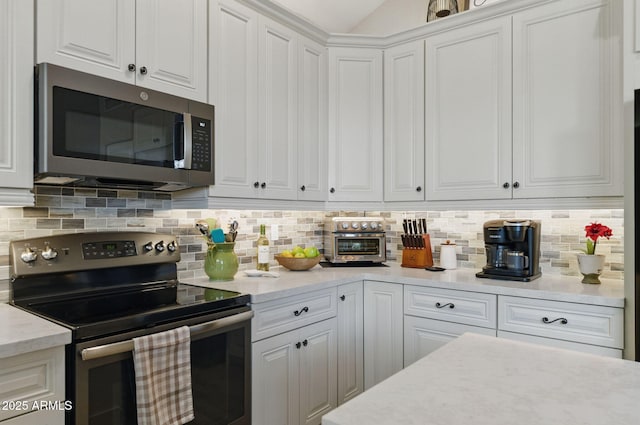 kitchen featuring a toaster, white cabinetry, light stone counters, backsplash, and stainless steel appliances