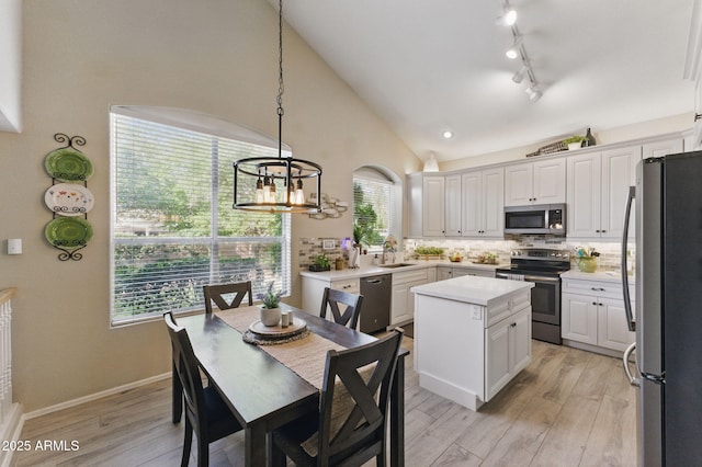 kitchen with a kitchen island, light countertops, tasteful backsplash, a sink, and appliances with stainless steel finishes