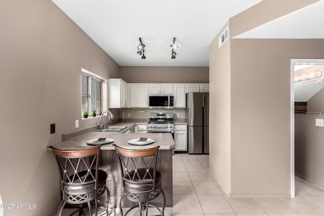 kitchen featuring white cabinetry, sink, stainless steel appliances, a kitchen breakfast bar, and light tile patterned flooring