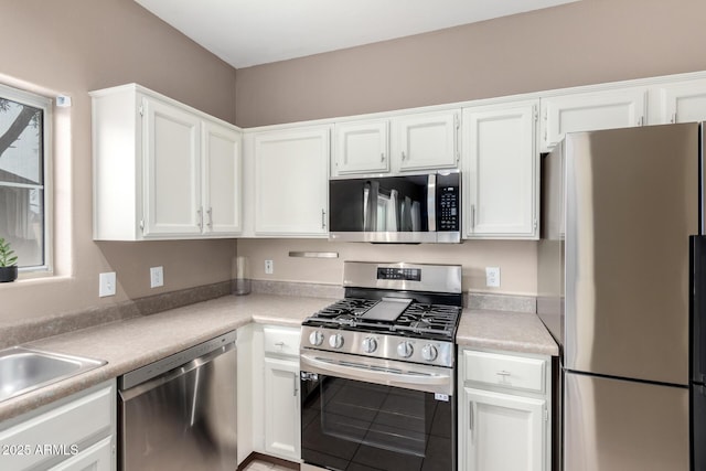 kitchen with stainless steel appliances, white cabinetry, and sink