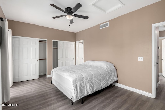 bedroom featuring multiple closets, ceiling fan, and dark wood-type flooring