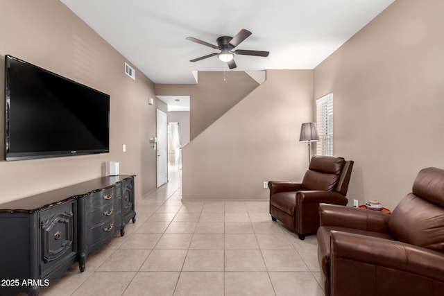 living room featuring a wood stove, ceiling fan, and light tile patterned flooring