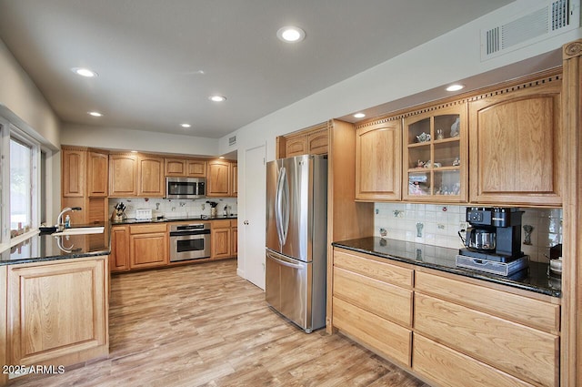 kitchen featuring visible vents, light wood-style flooring, appliances with stainless steel finishes, glass insert cabinets, and a sink