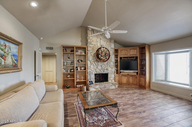 living area featuring visible vents, ceiling fan, a stone fireplace, wood finished floors, and high vaulted ceiling