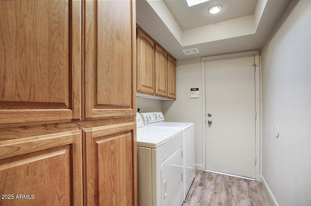 clothes washing area featuring cabinet space, baseboards, visible vents, independent washer and dryer, and light wood-type flooring