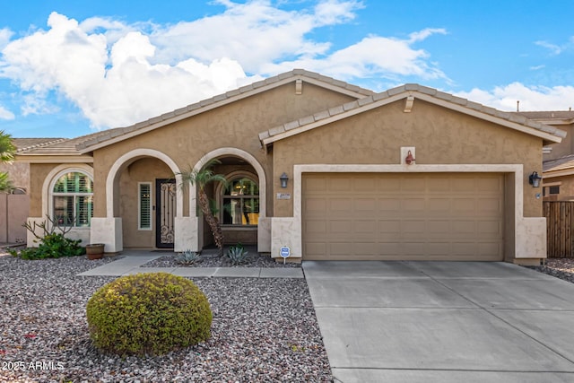 view of front of house featuring driveway, an attached garage, a tiled roof, and stucco siding