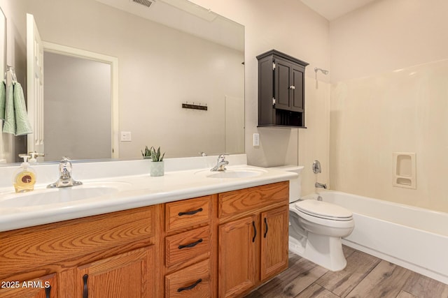 full bath featuring double vanity, a sink, toilet, and wood finished floors