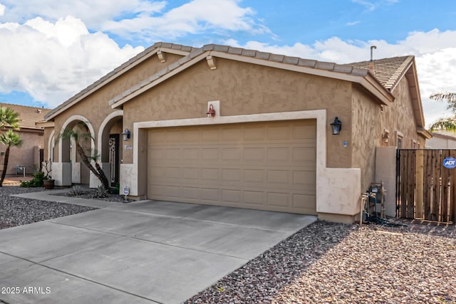 view of front of property featuring a garage, concrete driveway, a tile roof, and stucco siding