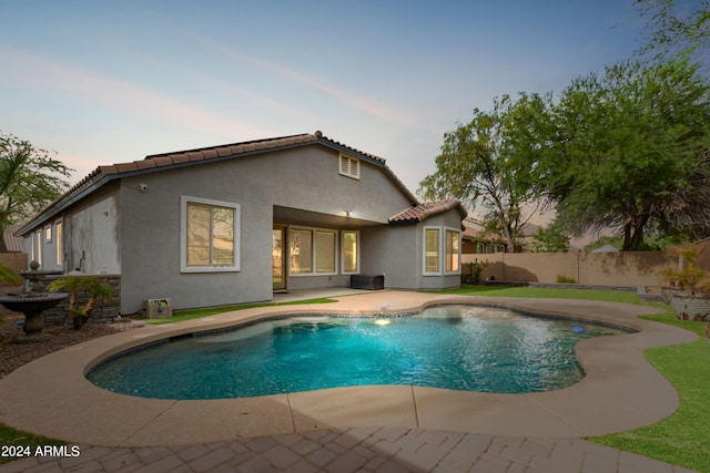 pool at dusk featuring a patio