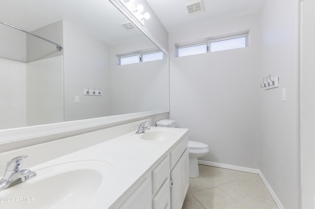 bathroom with tile patterned floors, vanity, a healthy amount of sunlight, and toilet