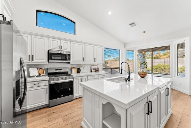 kitchen featuring appliances with stainless steel finishes, a kitchen island with sink, sink, and white cabinets