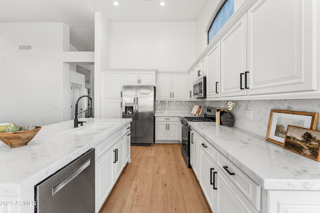 kitchen with sink, stainless steel appliances, an island with sink, and white cabinets