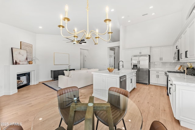 dining room with a towering ceiling, sink, a chandelier, and light hardwood / wood-style floors