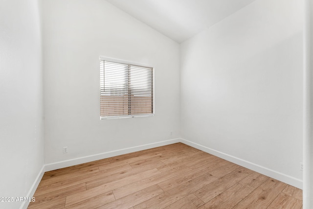 spare room featuring lofted ceiling and light hardwood / wood-style flooring