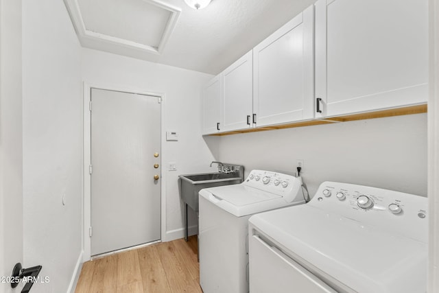 washroom featuring separate washer and dryer, sink, light hardwood / wood-style floors, and cabinets