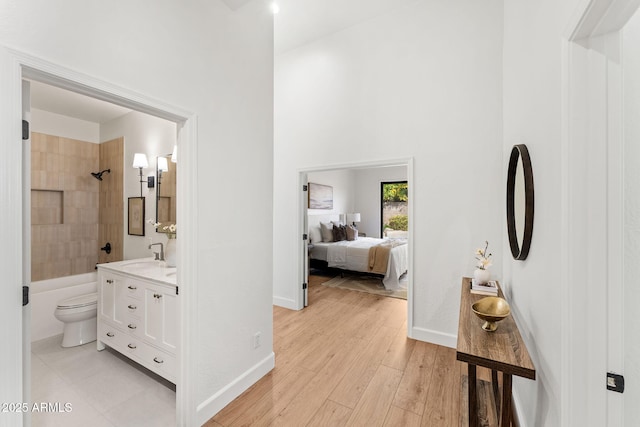 full bathroom with hardwood / wood-style flooring, a high ceiling, vanity, toilet, and tiled shower / bath