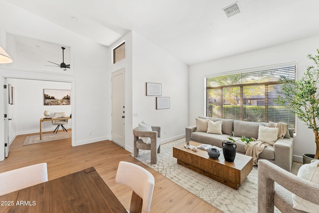 living room with ceiling fan, light hardwood / wood-style floors, and vaulted ceiling