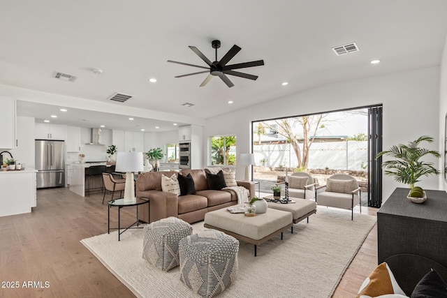 living area featuring light wood finished floors, visible vents, and ceiling fan