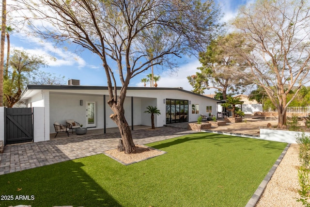 back of property featuring stucco siding, fence, a lawn, and a patio area