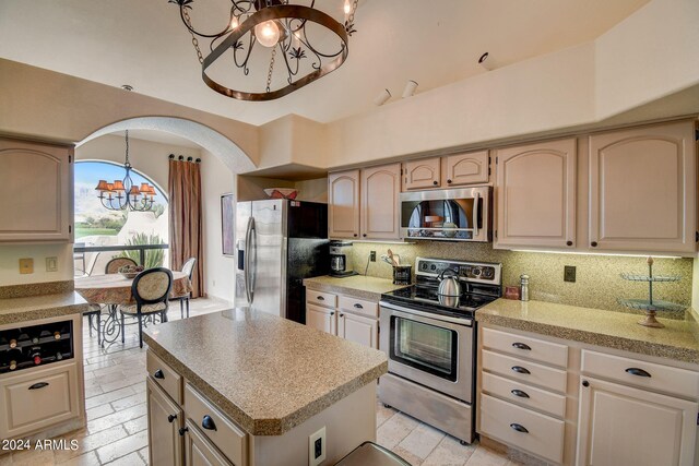 kitchen featuring light countertops, decorative backsplash, appliances with stainless steel finishes, and a chandelier