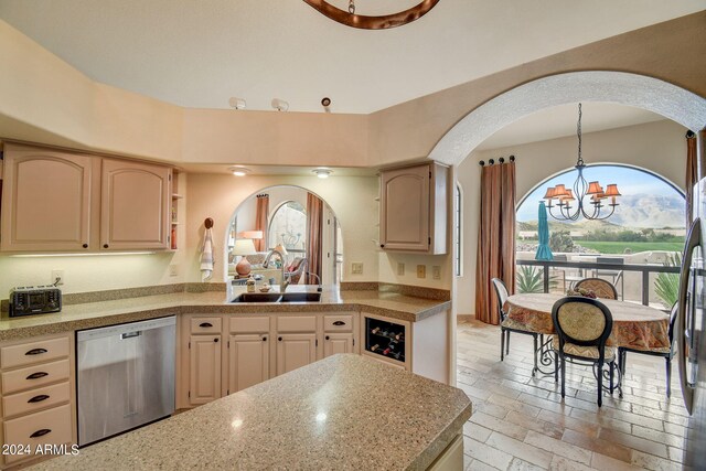 kitchen featuring stainless steel dishwasher, a sink, arched walkways, stone tile flooring, and a notable chandelier
