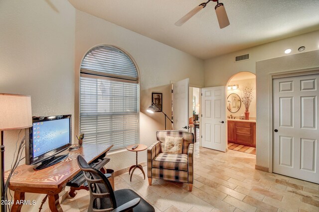 office with baseboards, visible vents, arched walkways, and ceiling fan