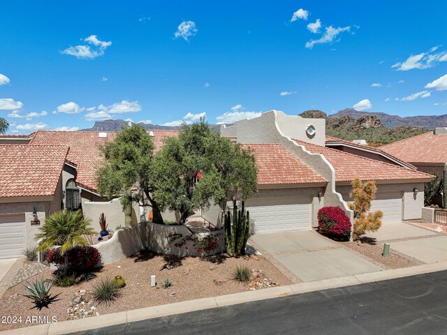 view of front of property featuring driveway, an attached garage, a tile roof, stucco siding, and a mountain view