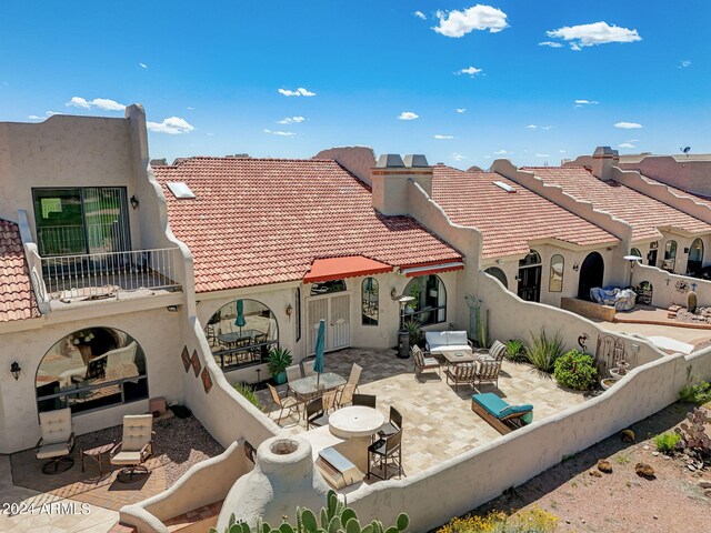 rear view of house featuring a patio, a tile roof, an outdoor living space, and a chimney