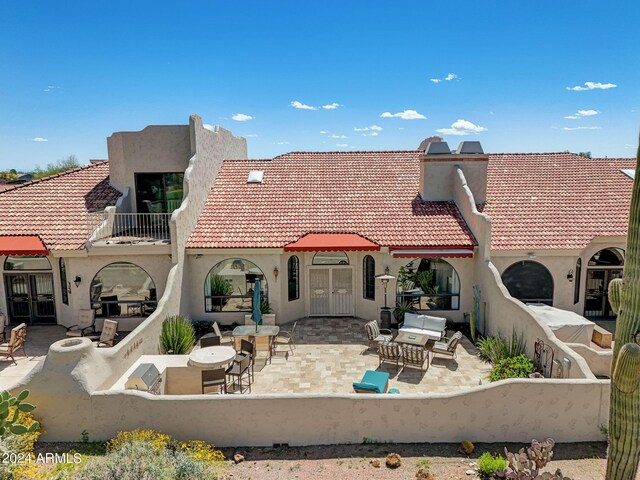 rear view of house featuring a tiled roof, a balcony, stucco siding, and a patio